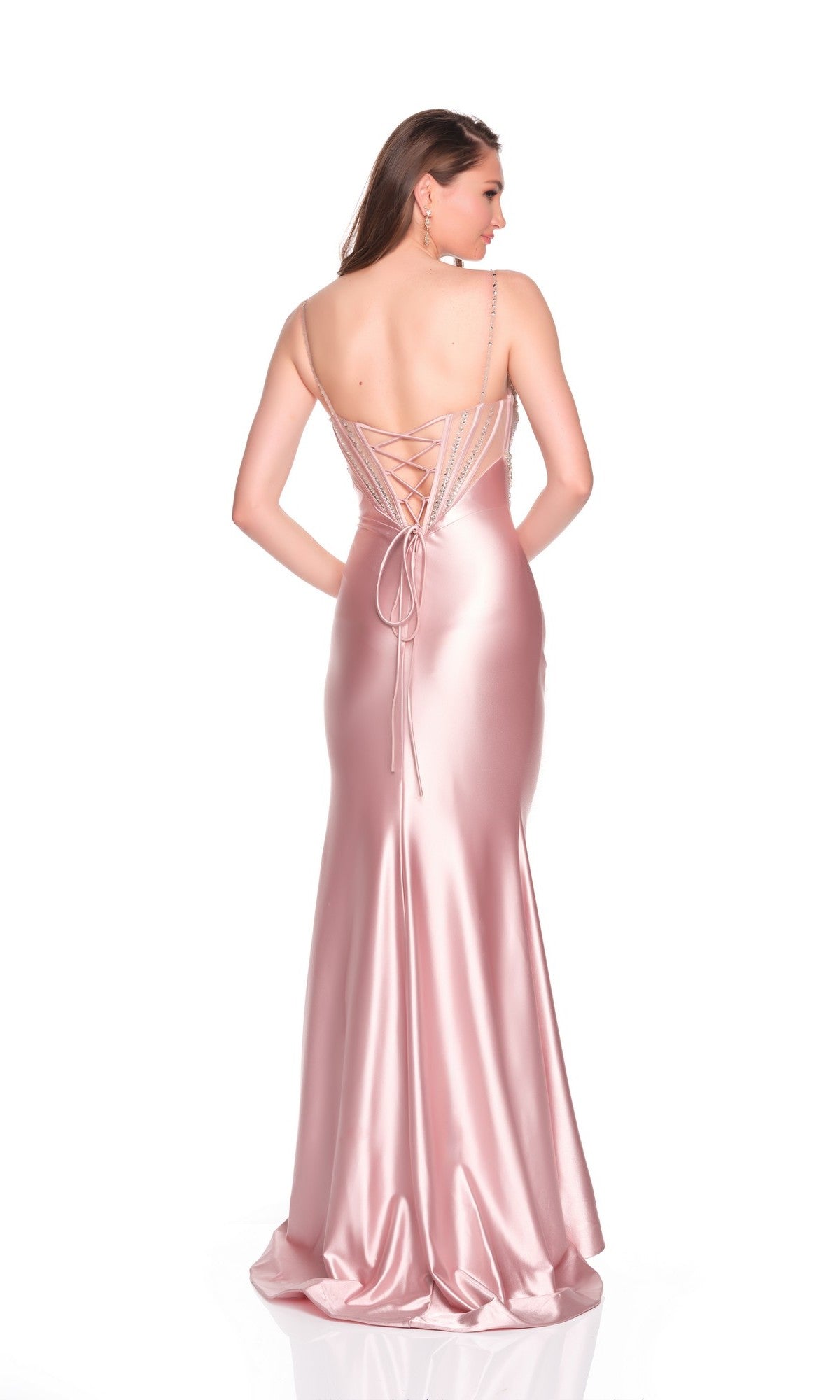 A woman is shown from the back in the Long Prom Dress: Dave and Johnny 12899, a pink fitted gown with spaghetti straps, a lace-up hot-stone embellished corset, and a floor-length satin skirt.